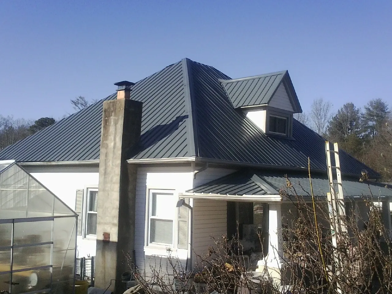 Dark blue standing seam metal roof on a white farmhouse with dormer — Slate & Tile Roof Repair by Roofing Brothers in Wilberforce