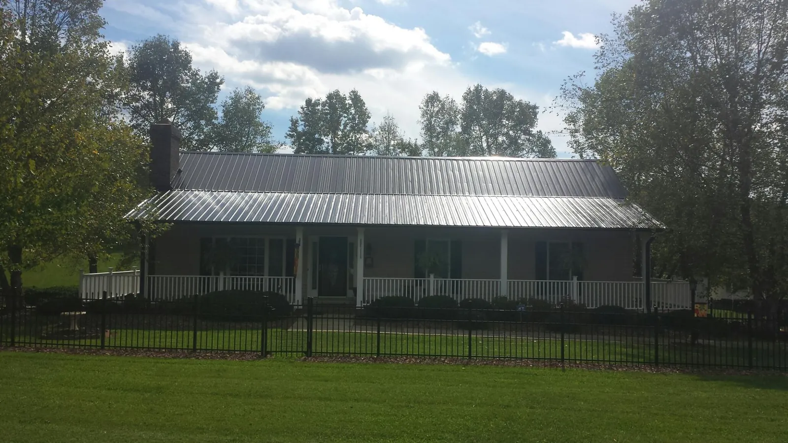 Gray metal roof on a brick ranch with a full width front porch — Gutter Guard Installation work by our crew in Wilberforce