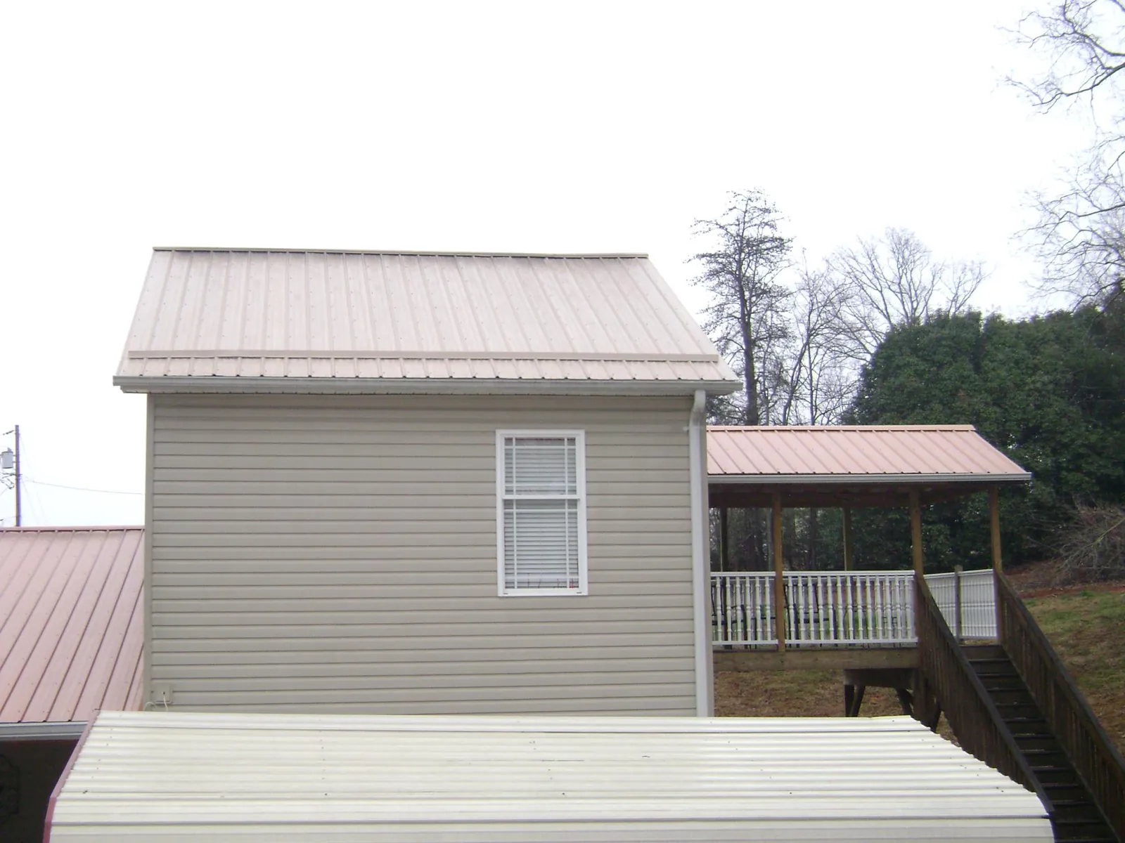 Tan metal roofs on a two story addition and attached porch, from a Roof Replacement job in Wilberforce