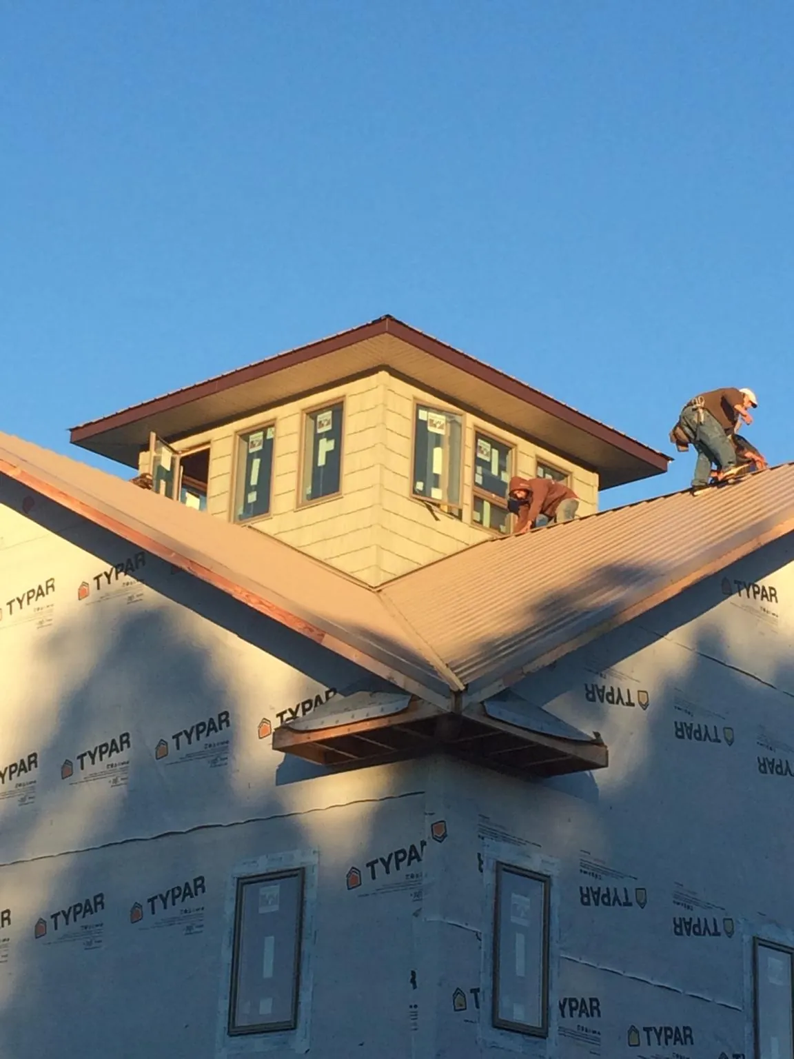 Roofers working around a rooftop cupola on a new metal roof at sunset — Roof Waterproofing in Wilberforce by Roofing Brothers